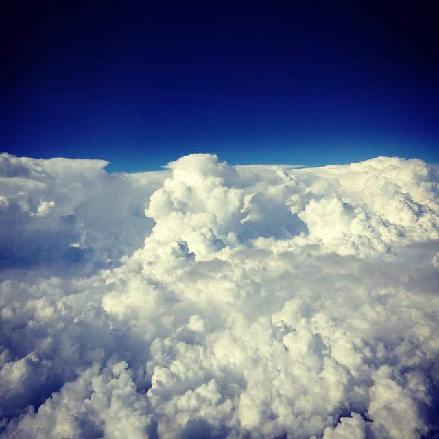 A stunning view of fluffy clouds against a deep blue sky from above.