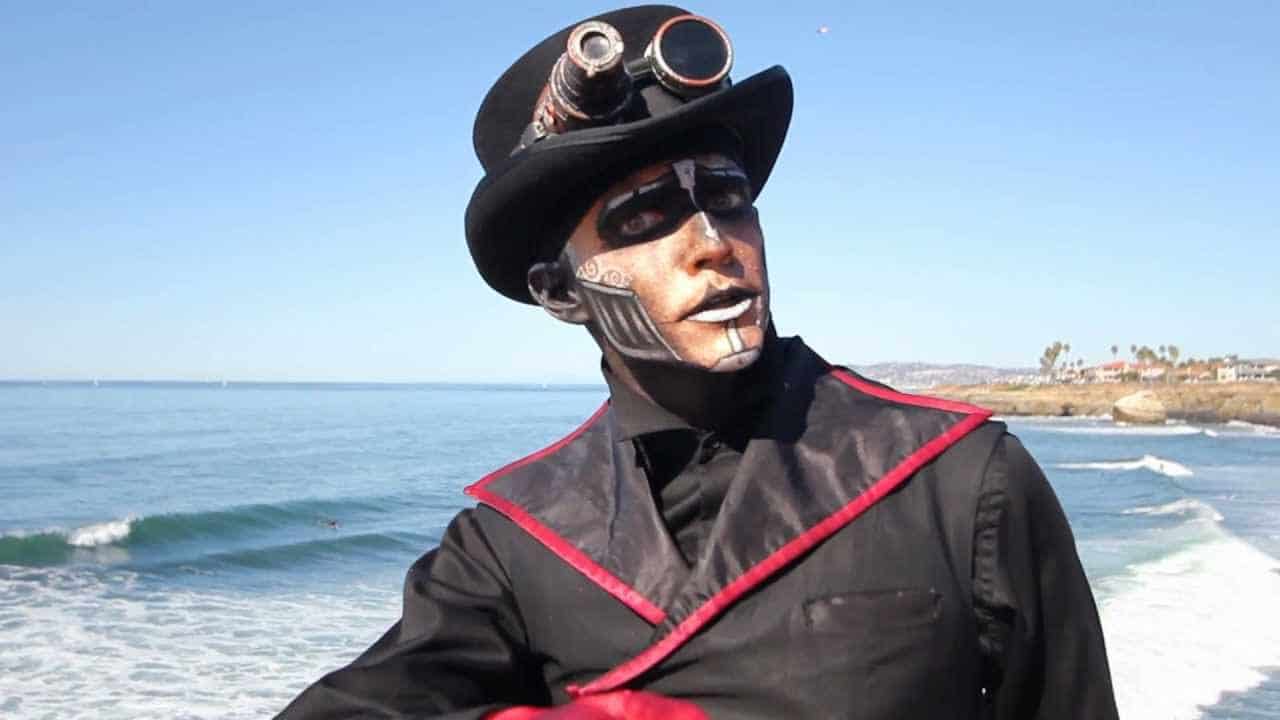 Steampunk character with goggles and face paint near the ocean.