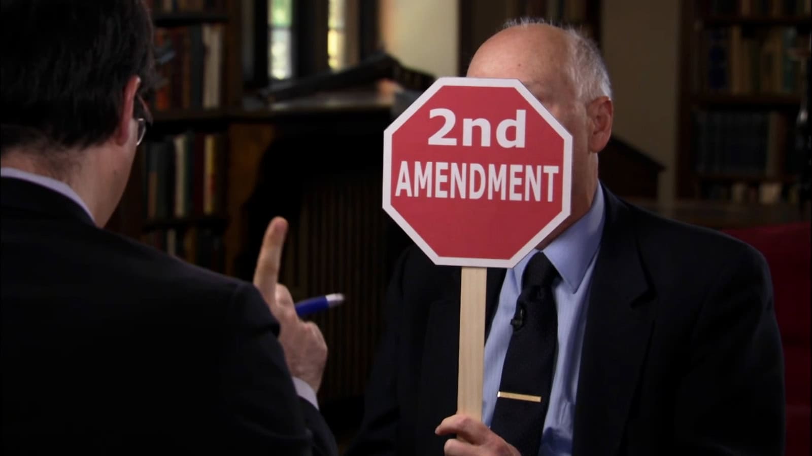 Protesters debate gun rights with a "2nd Amendment" sign during a discussion in a library.